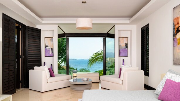 A modern bedroom with a large bed, two white sofas, a round coffee table, and a view of the ocean. - Hacienda de Mita 506 by Tripwix (Punta de Mita)