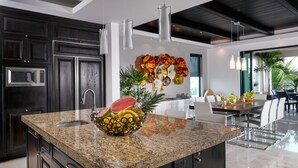 A modern kitchen with granite countertops, stainless steel appliances, and a central island with a fruit bowl. - Hacienda de Mita 506 by Tripwix (Punta de Mita)