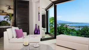 A modern living room with a white sofa, a round coffee table, and a view of a coastal landscape. - Hacienda de Mita 506 by Tripwix (Punta de Mita)