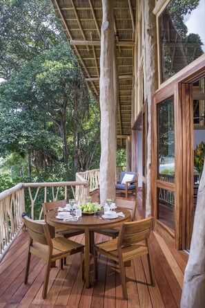 A wooden deck with a round table and chairs, surrounded by a wooden railing. - Treehouse Punta Sayulita by Tripwix (Sayulita)