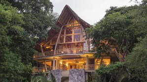 A large, multi-story building with a wooden exterior and balconies, surrounded by dense foliage. - Treehouse Punta Sayulita by Tripwix (Sayulita)