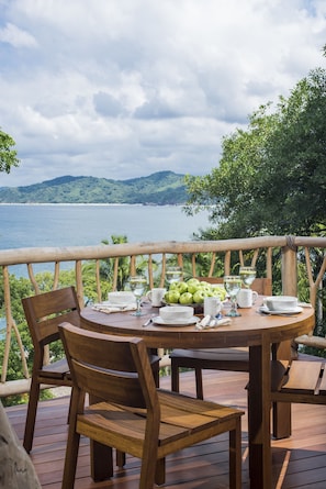A wooden deck with a round table set for dining, overlooking a body of water and greenery. - Treehouse Punta Sayulita by Tripwix (Sayulita)