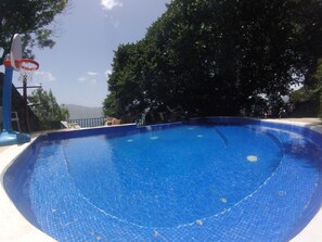 Een buitenzwembad, ligstoelen bij het zwembad