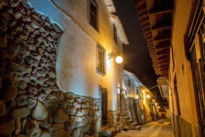 A narrow street with stone walls and traditional buildings at night. - Tariq Boutique (Cusco)