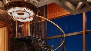 Ein modernes Interieur mit einer Wendeltreppe, Ledersitzmöbeln und Blick auf die Stadt.