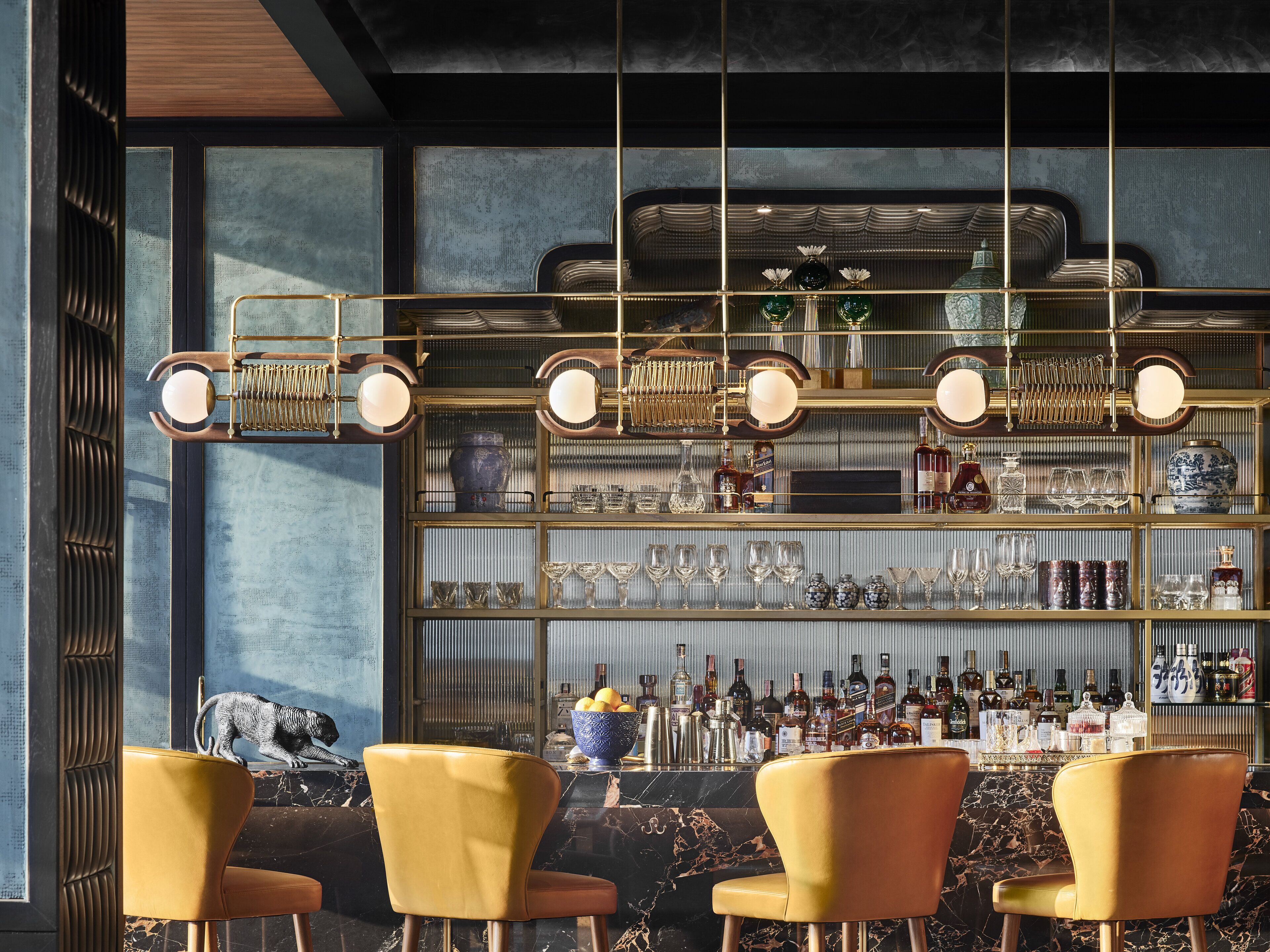 A bar area with gold-framed shelves, various bottles, and a marble countertop.