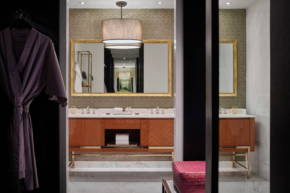 Un baño moderno con tocador doble, un espejo grande y una bata colgada en un perchero.