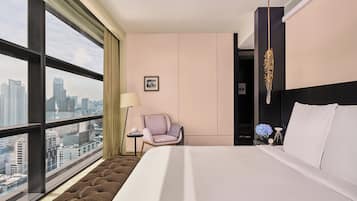 A hotel room with a large window, a bed, a chair, and a nightstand.