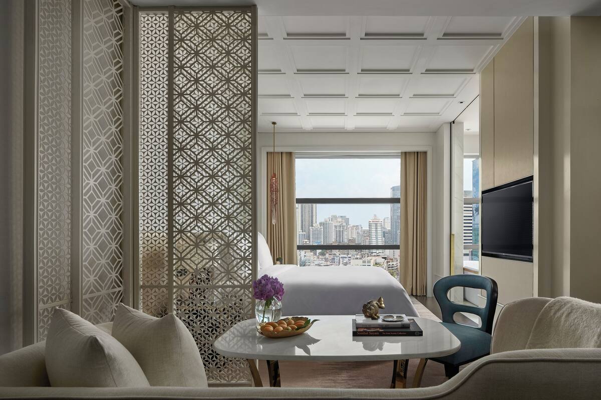 Habitación de hotel moderna con vista a la ciudad, una mesa de comedor redonda y un sofá.