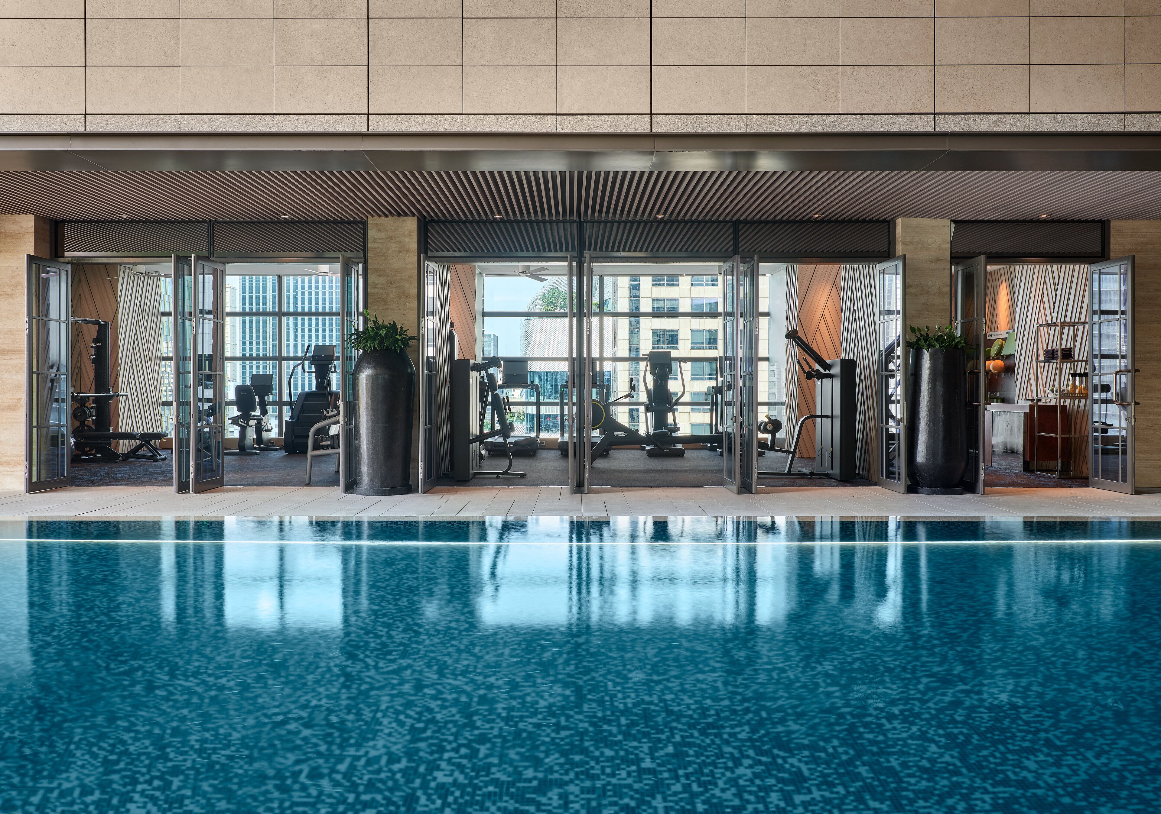 An indoor swimming pool with exercise equipment and a view of the city.