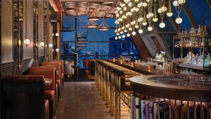 Eine Bar mit Blick auf die Stadt, einer Wendeltreppe und verschiedenen Sitzgelegenheiten.