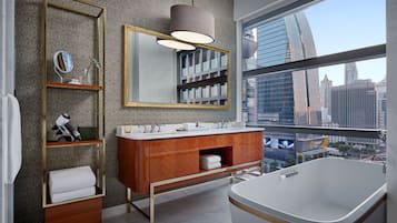 A modern bathroom with a large window, a vanity with a mirror, and a bathtub.
