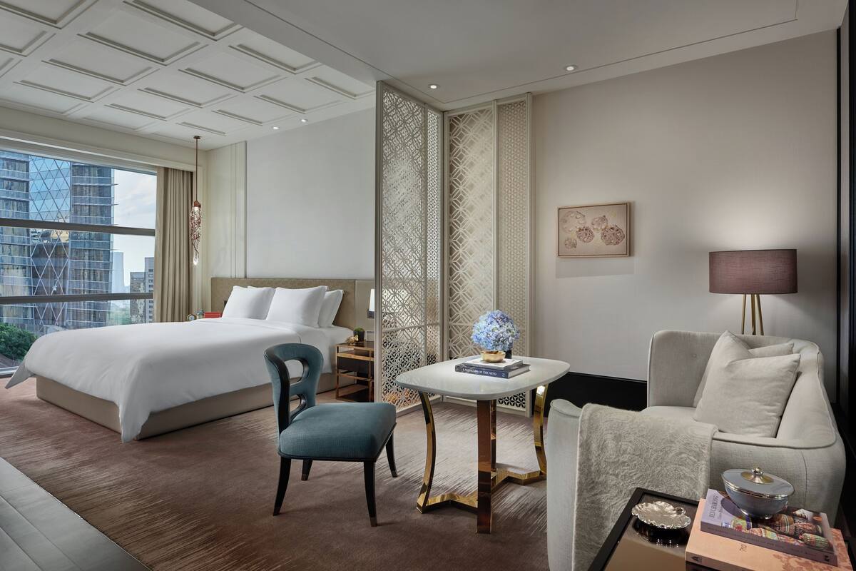 Habitación de hotel con una cama grande, un escritorio, una silla, un sofá y vistas a la ciudad.