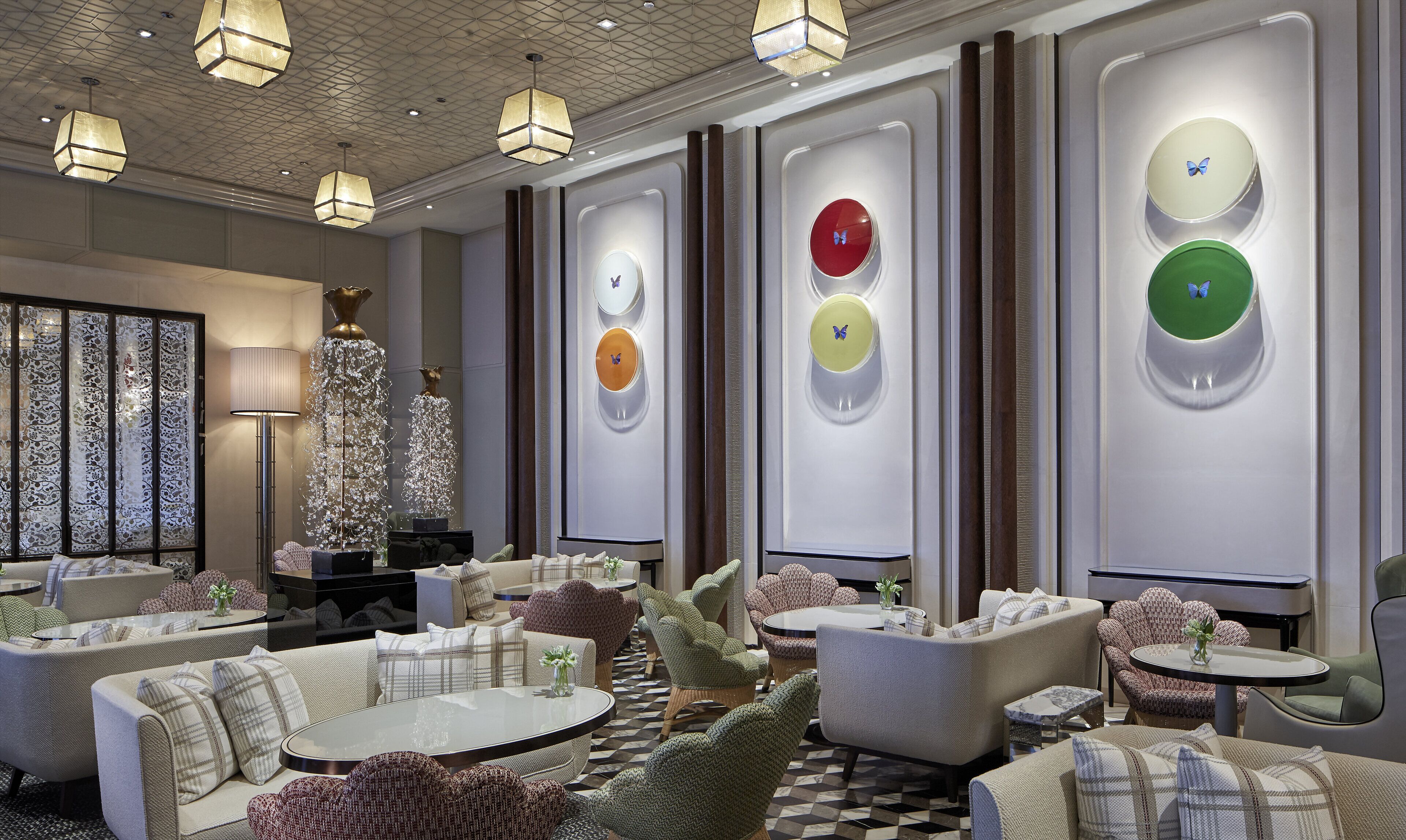 A modern lounge area with sofas, tables, and decorative wall clocks.