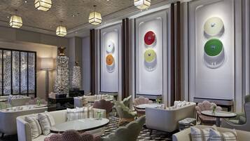 A modern lounge area with sofas, tables, and decorative wall clocks.