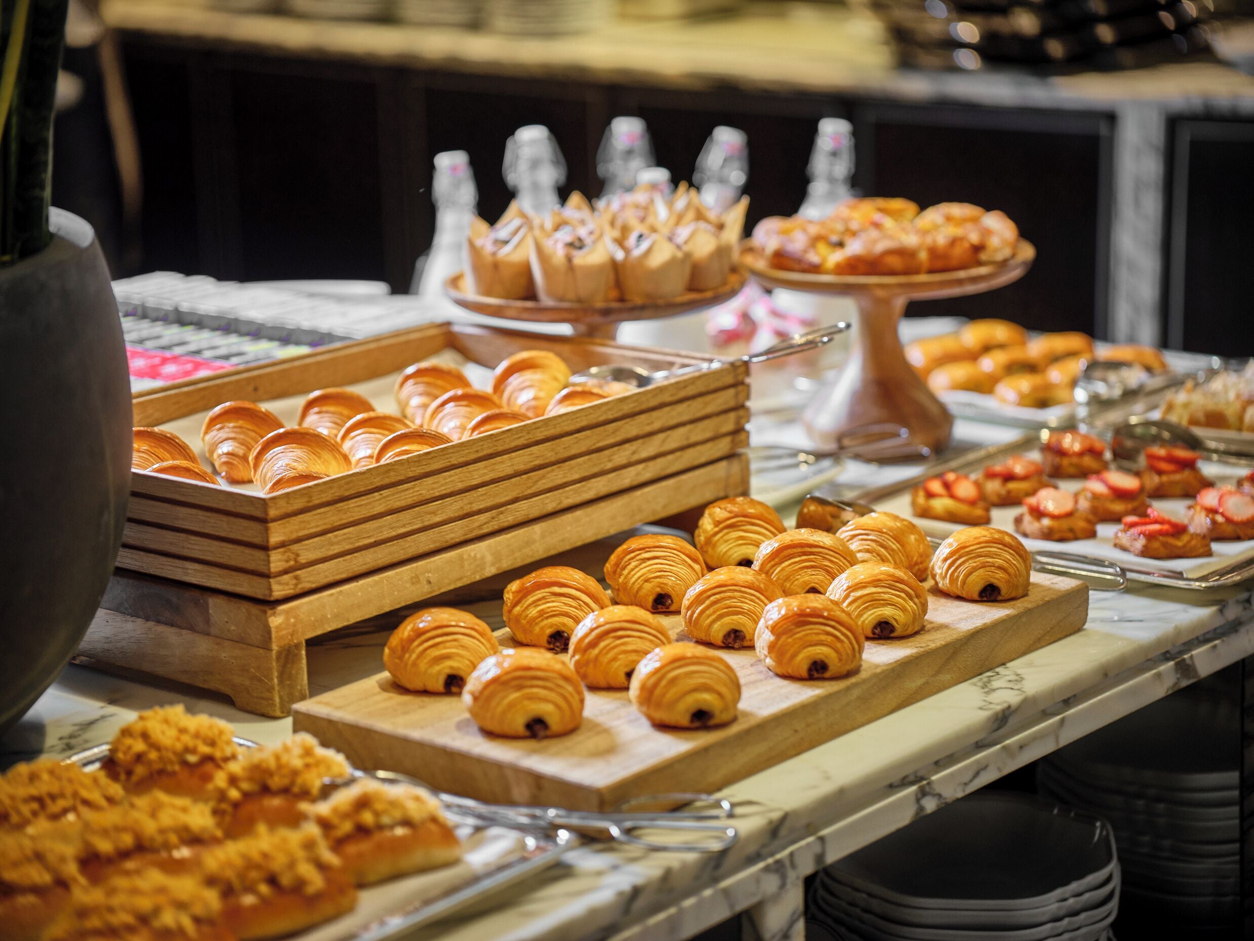 A buffet with various pastries and desserts, including croissants and fruit-topped pastries.
