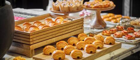 A buffet with various pastries and desserts, including croissants and fruit-topped pastries.