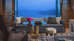 A modern living room with a sofa, a coffee table, and a view of a cityscape through large windows.