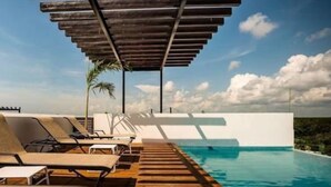 Ein Poolbereich mit Holzterrasse, Liegestühlen und einer Pergola.