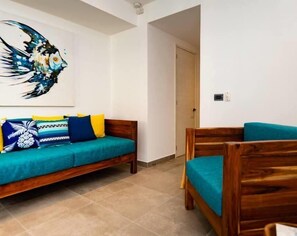 A room with two wooden beds, a blue sofa, and a colorful painting on the wall.