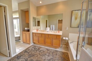 A modern bathroom with a large vanity, double sinks, a glass shower enclosure, and a large mirror. - Bella Baranda (Palm Desert)