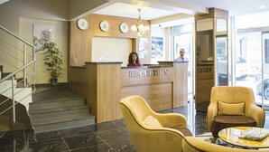 Et receptionsområde med en træreception, en trappe og to lænestole.