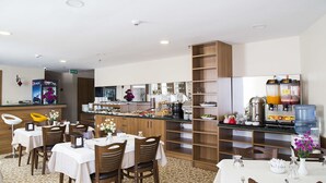 Et hotelspisested med borde, stole, en buffet og kaffestation.