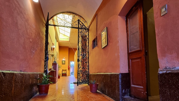 A corridor with a tiled floor, a decorative gate, and a door on the right.