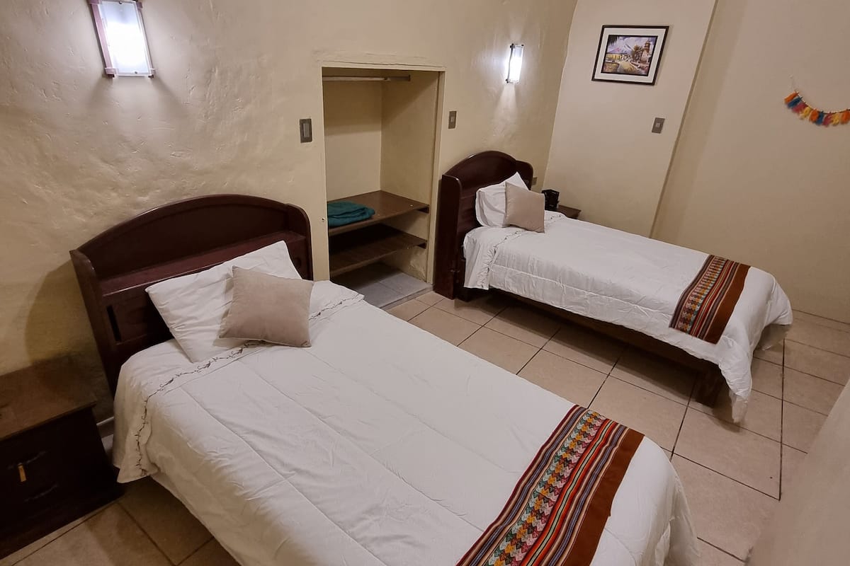 A room with two beds, a small closet, and a picture on the wall.