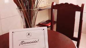 A dining table with a card that reads "Bienvenido!" and a vase with dried plants. - Casona de Sillar (Arequipa)