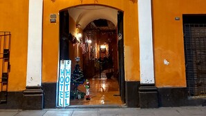 A hotel entrance with an arched doorway, a signboard, and decorative lights.