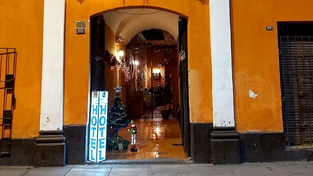 A hotel entrance with an arched doorway, a signboard, and decorative lights. - Casona de Sillar (Arequipa)