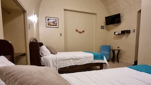 A room with two beds, a television mounted on the wall, and a small table. - Casona de Sillar (Arequipa)
