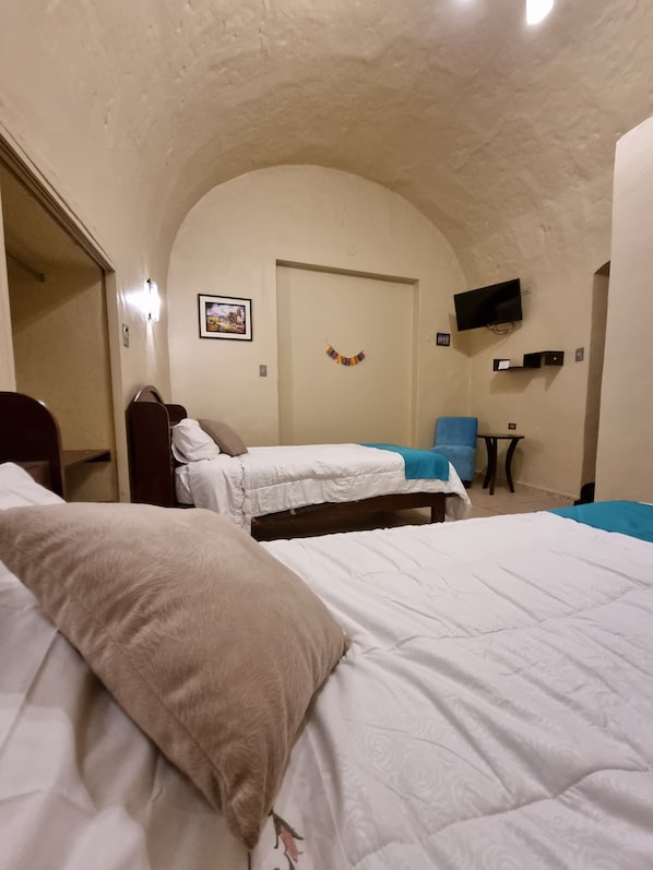 A room with two beds, a television mounted on the wall, and a small table. - Casona de Sillar (Arequipa)