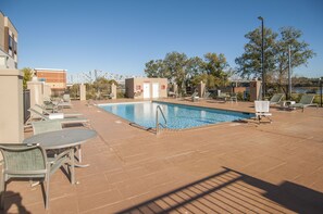 Un espace piscine avec des chaises longues et un petit bâtiment sur lequel est apposée une enseigne.