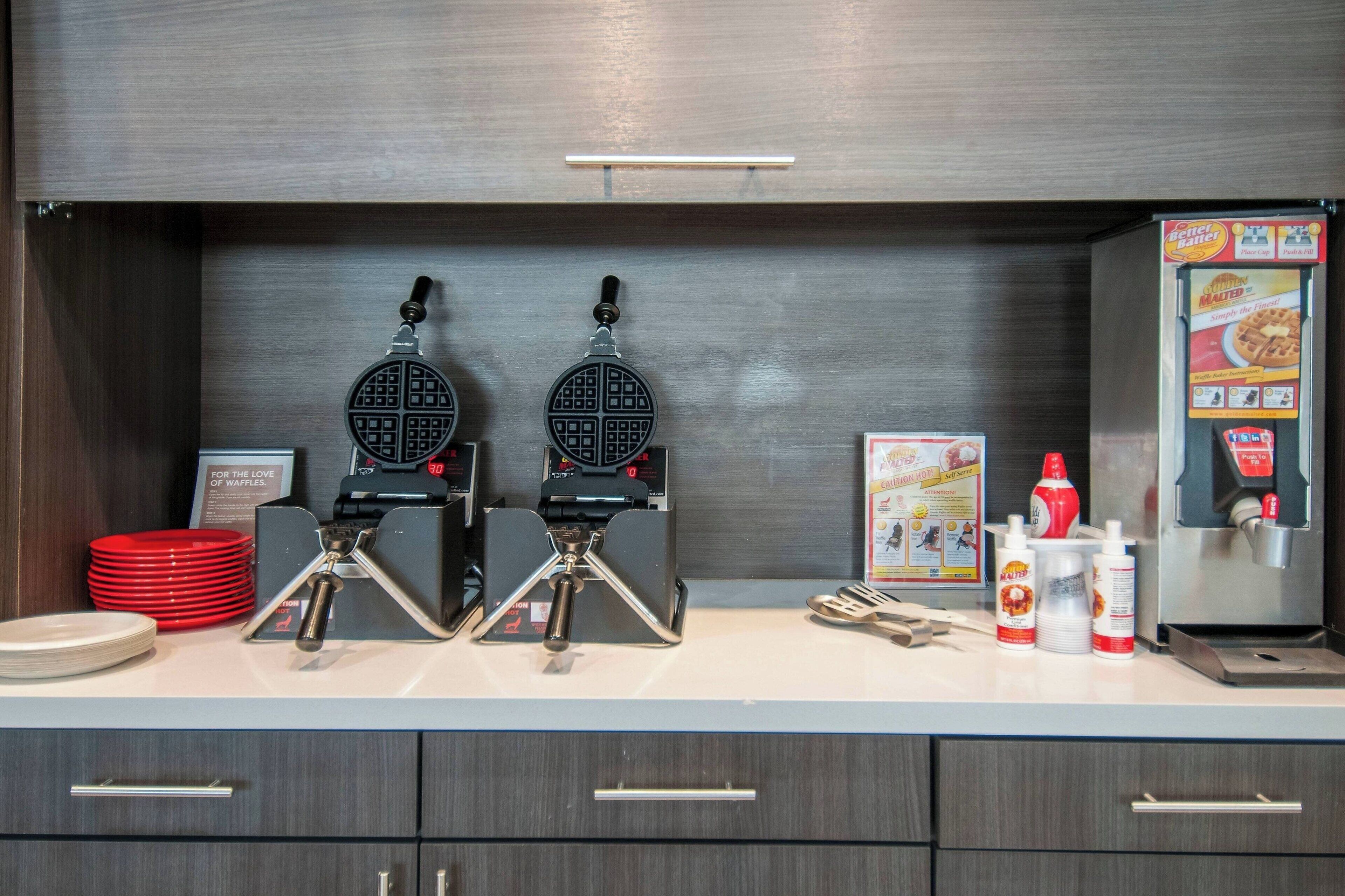 Un espace cuisine équipé de deux gaufriers, d’une machine à gaufres et d’un distributeur de gaufres.