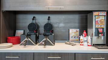 Un espace cuisine équipé de deux gaufriers, d’une machine à gaufres et d’un distributeur de gaufres.