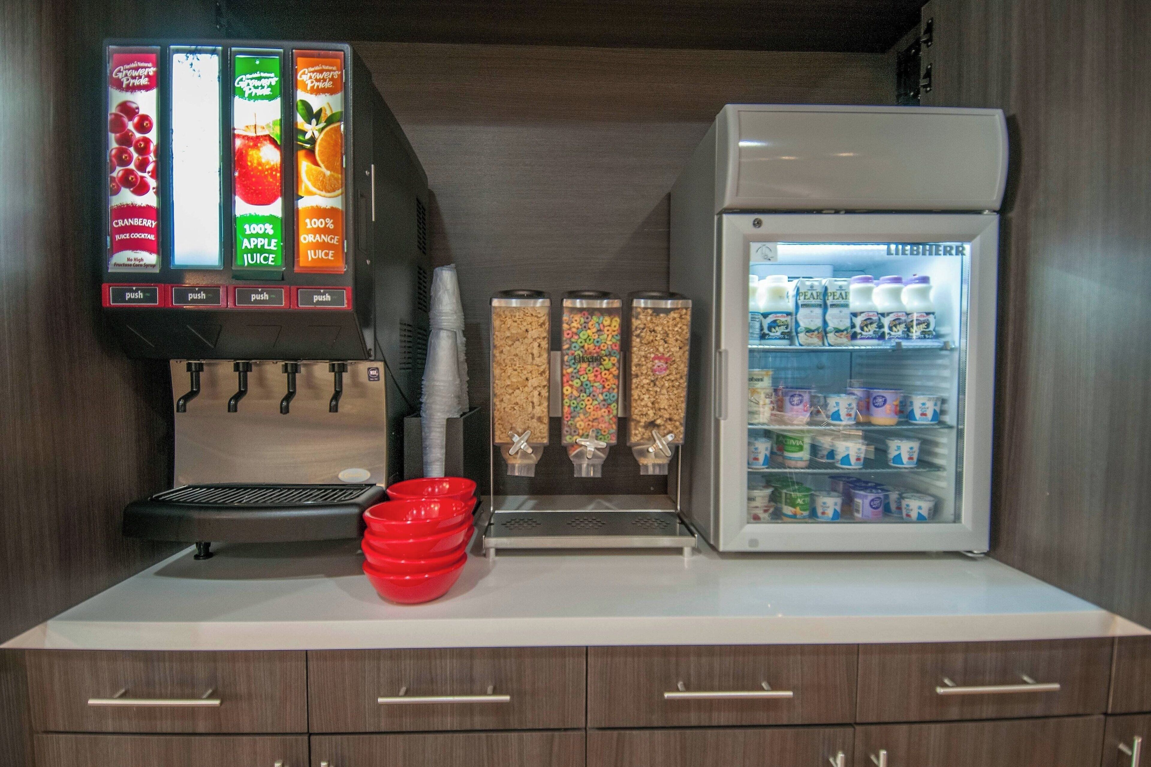 A beverage station with a coffee machine and a refrigerator stocked with drinks.