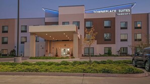 Un hotel townhouse con diseño moderno, que cuenta con un acceso cubierto y un jardín bien cuidado.