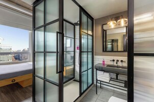 A modern bathroom with a glass-enclosed shower, a large mirror, and a sink with a towel rack.