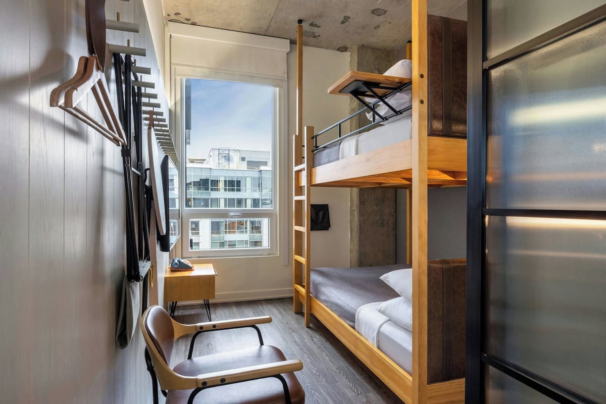 A compact room with bunk beds, a desk, and a chair.