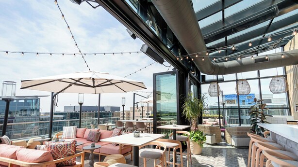 A rooftop terrace with outdoor seating, large umbrellas, and string lights. - Moxy Washington DC Downtown (Washington)