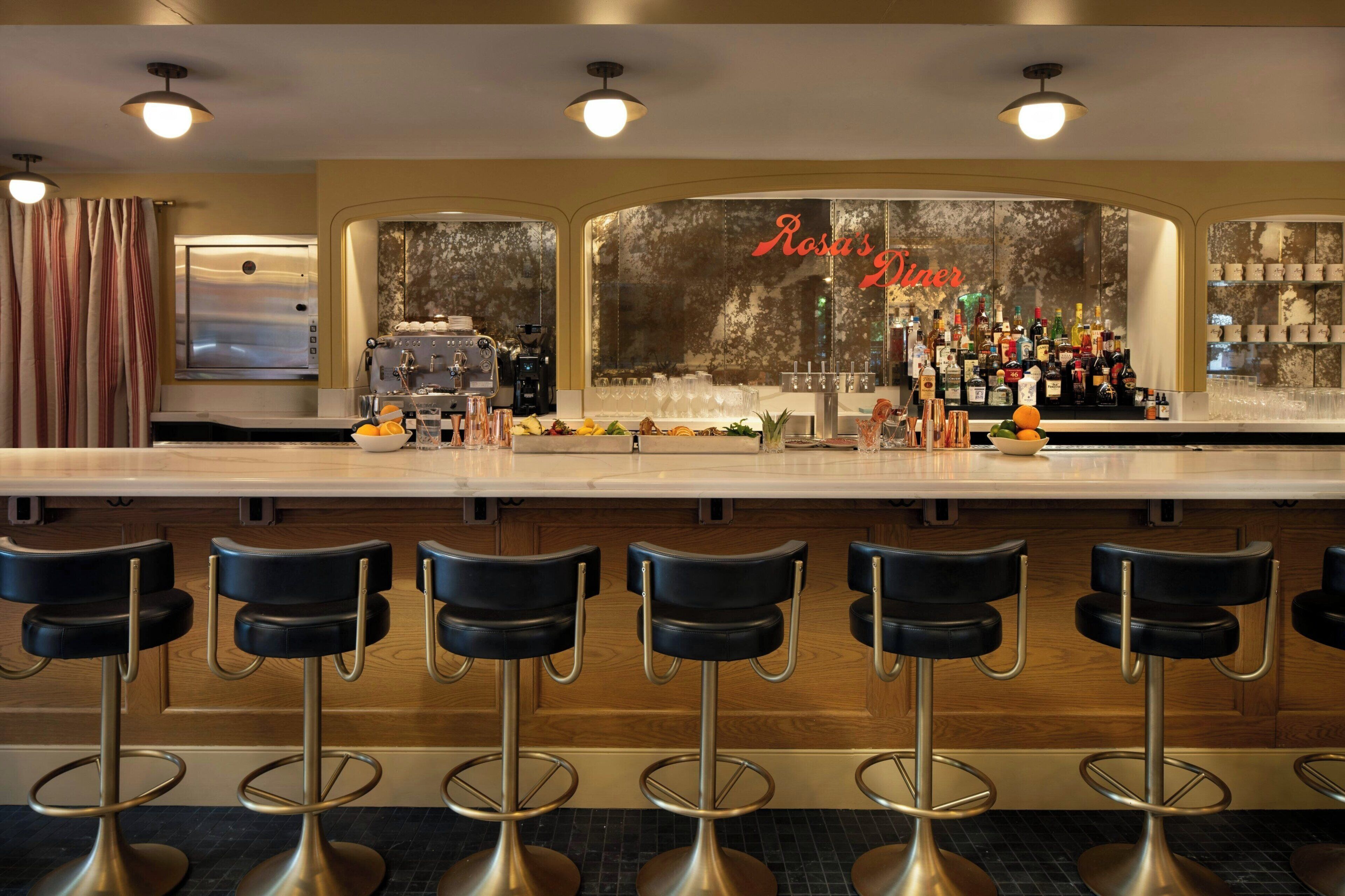 A bar area with a counter, bar stools, and a variety of bottles and glasses.