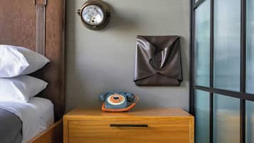 Un dormitorio con una cama, una mesita de noche de madera, un reloj y cuadros en la pared.