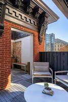 Une terrasse avec une table blanche, deux chaises et un pot de fleurs.