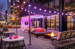Un espace extérieur aménagé avec des tables et des chaises, un foyer et un espace de détente couvert avec des coussins.