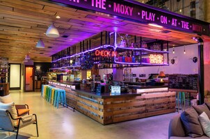 A bar area with a neon sign, stools, and a check-in counter.