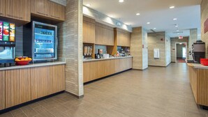 Un moderno vestíbulo de hotel con paneles de madera, una estación de bebidas de autoservicio y una recepción.