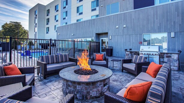 Un patio de hotel con mobiliario exterior, una fogata y una parrilla.