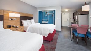 Habitación de hotel con dos camas, un escritorio, una silla, un refrigerador y un microondas.